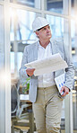 Mature man, blueprint and construction manager walking in building site, project management and design. Engineering, contractor and thinking of floor plan for architecture, development and innovation