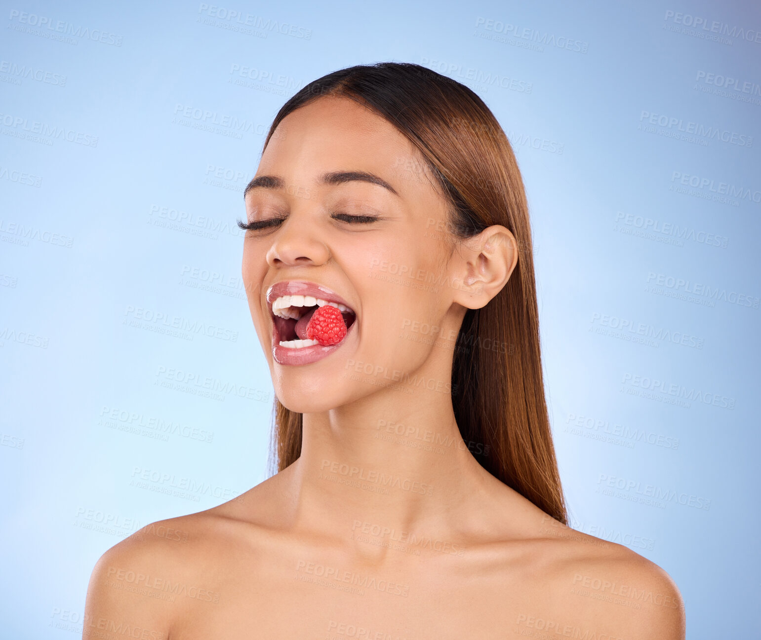 Buy stock photo Beauty, woman and face with raspberry for skincare dermatology cosmetics in studio. Female model person on a blue background for self care, facial glow and healthy or clean skin with natural fruit