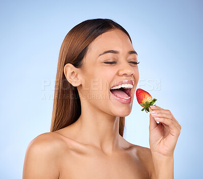 Buy stock photo Skincare, health and female with a strawberry in studio with a wellness, natural and face routine. Happy, beauty and woman model eating red fruit for nutrition, diet and self care by blue background.