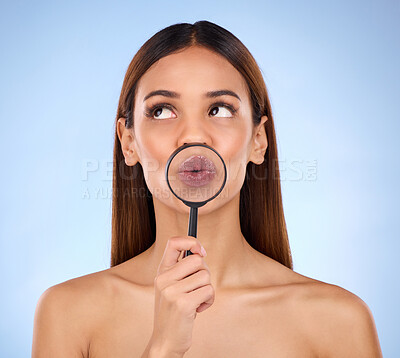 Buy stock photo Pouting, skincare and a woman with a magnifying glass on mouth isolated on a blue background. Goofy, thinking and a girl with a tool for a closeup on lips, beauty and cosmetics on a backdrop