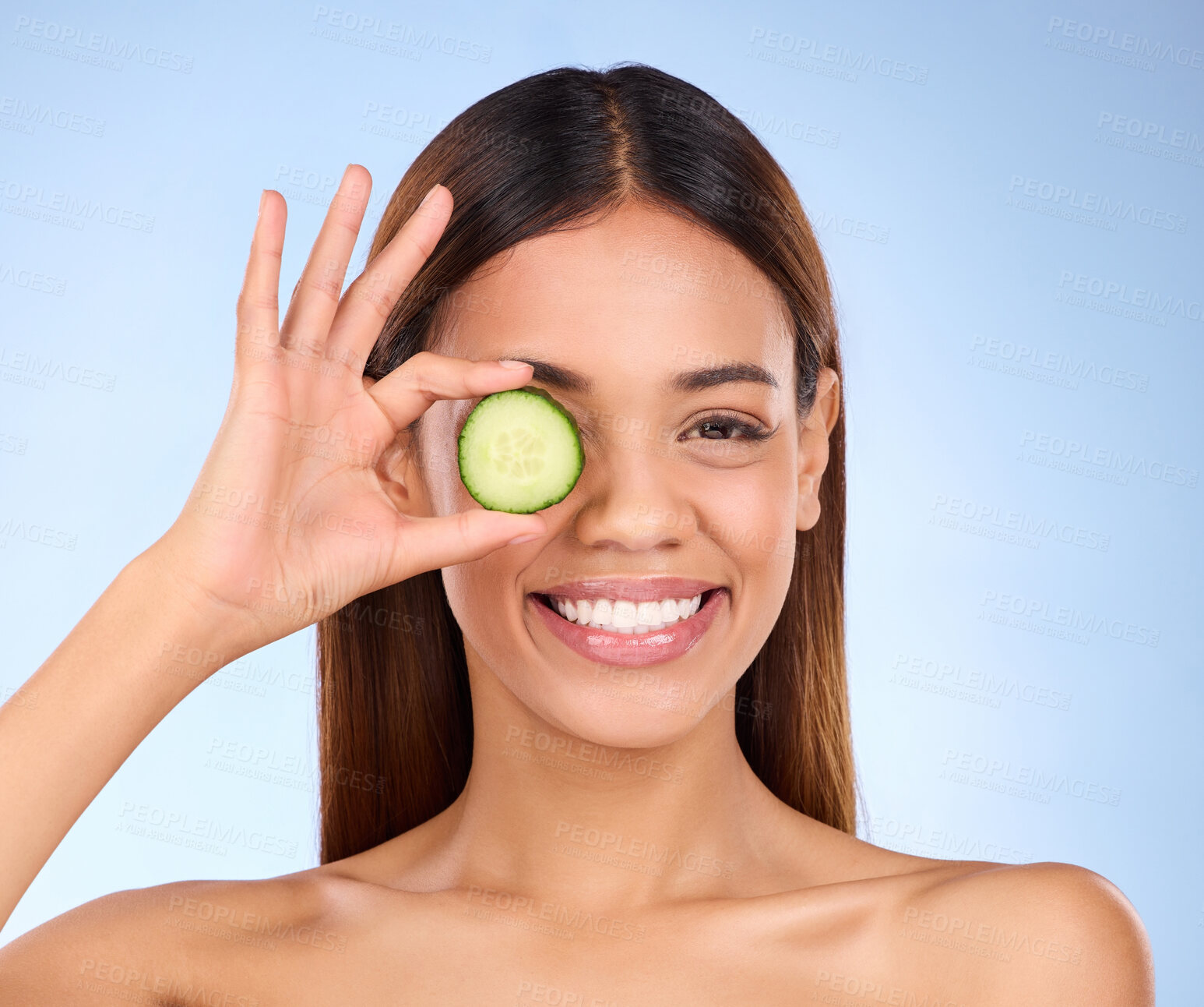 Buy stock photo Beauty, woman and cucumber for face portrait with a smile and dermatology skincare cosmetic. Female model on blue background for self care, facial glow and vegetable for natural skin health in studio