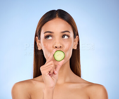 Buy stock photo Cucumber, woman and skincare face portrait with beauty and dermatology cosmetics. Female model on a blue background thinking about self care, facial glow and healthy fruit for natural skin in studio