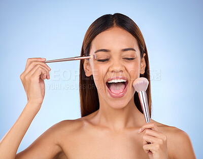 Beauty, woman and brush for makeup on face with cosmetics in studio. Aesthetic female model person on a blue background excited for self care, facial glow and application for powder and shine on skin