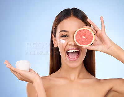 Buy stock photo Woman, moisturizer cream and grapefruit for natural skincare beauty and vitamin C against blue studio background. Portrait of happy female holding fruit, creme or lotion for healthy organic products