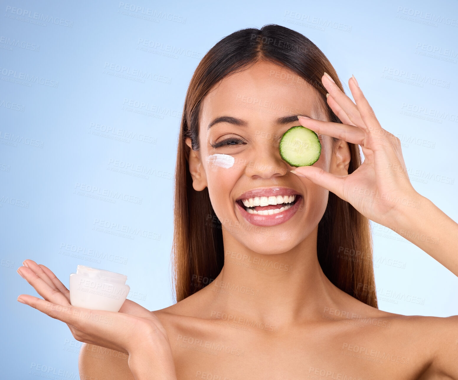 Buy stock photo Woman, moisturizer cream and cucumber for natural skincare, beauty and cosmetics against blue studio background. Portrait of happy female holding vegetable, creme or lotion for healthy organic facial