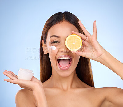 Buy stock photo Woman, moisturizer cream and lemon for natural skincare, beauty and vitamin C against blue studio background. Portrait of happy female holding citrus fruit, creme or lotion for healthy organic facial