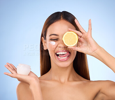 Buy stock photo Woman, moisturizer cream and lemon for natural skincare, beauty and vitamin C against a blue studio background. Female holding citrus fruit, creme or lotion for healthy organic nutrition or facial