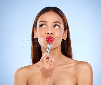 Buy stock photo Beauty, woman and thinking about red lipstick or makeup with face cosmetics in studio. Aesthetic female model on a blue background to think self care, facial glow and color application for lips idea