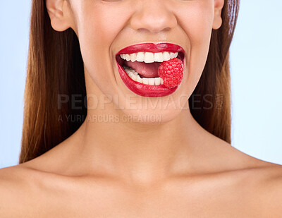 Buy stock photo Beauty, health and raspberry with mouth of woman in studio for nutrition, diet or detox. Cosmetics, natural and self care with girl model eating fruit on blue background for wellness, organic or glow