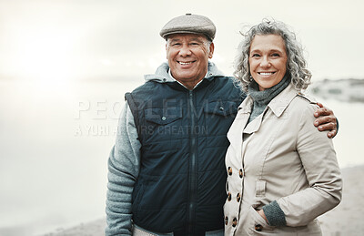 Buy stock photo Portrait, winter and senior couple hug, beach for holiday or anniversary getaway with joy, smile or retirement. Face, old woman or mature man embrace, happiness or loving together for romance or love