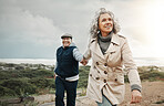 Beach, love and senior couple holding hands on romantic evening walk in nature on happy date. Smile, romance and retirement, old woman and man walking on ocean path at sunset on holiday in Australia.