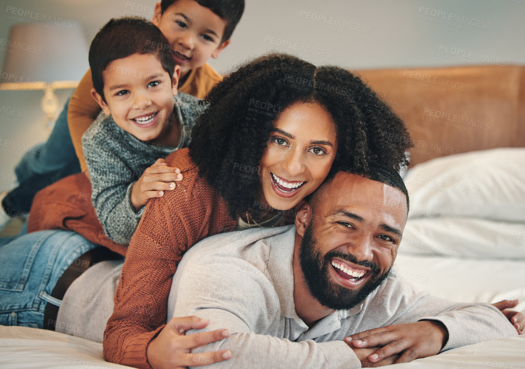 Buy stock photo Family, laughing and portrait smile on bed in bedroom, bonding and care in home. Love, interracial and happy mother, comic father and funny children playing, having fun and enjoying time together.