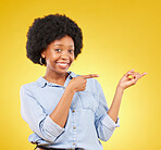 Happy, portrait of a black woman in studio pointing at mockup space for advertising or marketing. Happiness, smile and African female model showing mock up for product placement by yellow background.