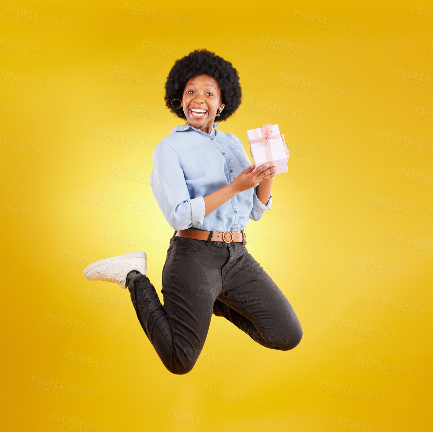 Buy stock photo Jump, excited and black woman with gift in air on yellow background with energy, happy and smile in studio. Birthday mockup, celebrate and isolated girl jumping with present, box and surprise package