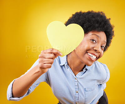 Buy stock photo Portrait, heart and social media with a black woman in studio on a yellow background for love or affection. Emoji, shape and romance with an attractive young female feeling excited for valentines day