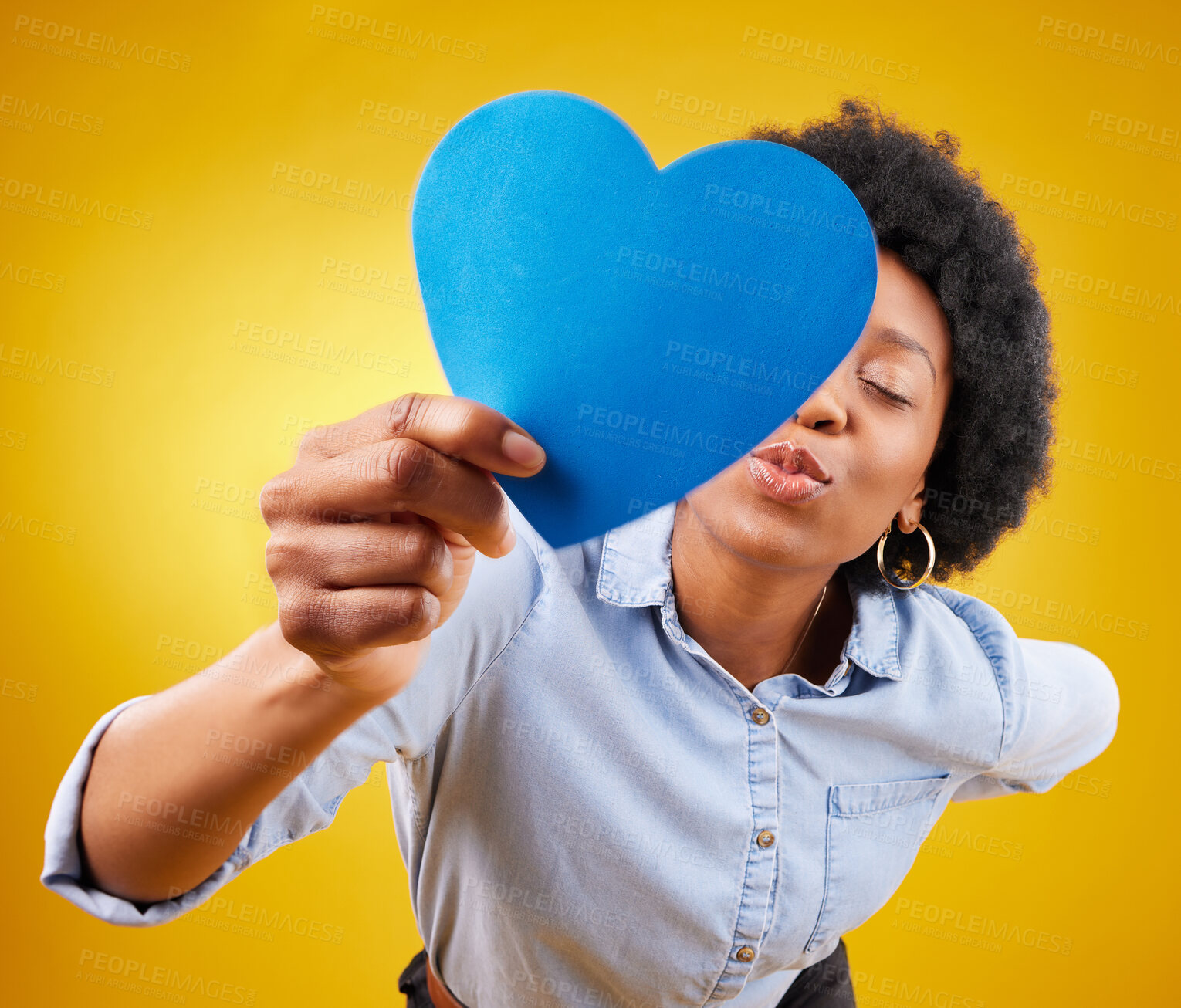 Buy stock photo Paper, heart and kissing with black woman in studio for romance, positive and emotion. Happiness, love shape and giving with female isolated on yellow background for date, feelings and affectionate