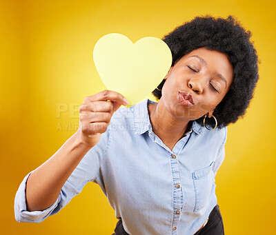 Buy stock photo Paper, heart and kiss with black woman in studio for romance, positive and emotion. Happiness, love shape and giving with female isolated on yellow background for date, feelings and affectionate