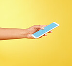 Hands, phone mockup and green screen in studio isolated on a yellow background. Cellphone, social media and black woman holding mobile smartphone for advertising space, marketing or product placement