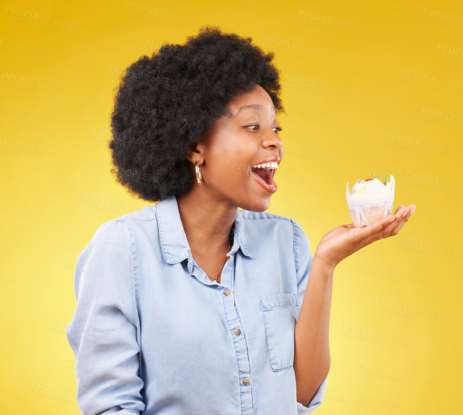 Buy stock photo Black woman, cupcake and excited or happy in studio while eating sweet food on a yellow background. African female model with snack, dessert or cake for happiness, birthday or celebration mockup