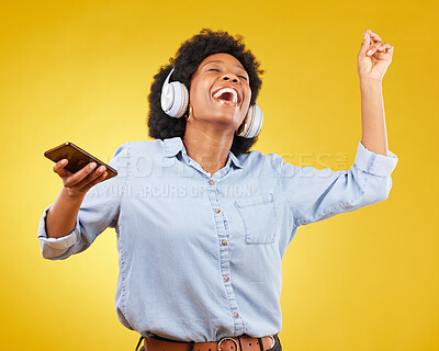 Buy stock photo Phone, music headphones and black woman singing in studio isolated on a yellow background. Dance, cellphone and happy female with mobile for streaming, dancing and enjoying radio, podcast or audio.