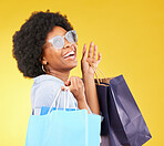 Shopping bag, retail and happy black woman with sales product, discount fashion deal or mall store present. Commerce market, luxury designer gift or chic studio customer isolated on yellow background