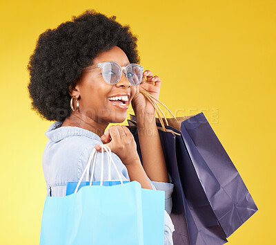 Buy stock photo Bag, portrait and black woman shopping, excited and celebrating sale in studio on yellow background. Face, shopper and girl customer cheerful after boutique, retail or store discount posing isolated