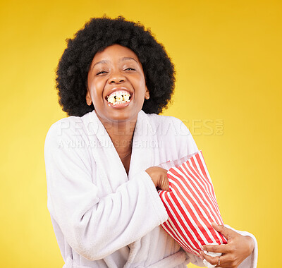 Buy stock photo Funny face, portrait and black woman eating popcorn in studio isolated on a yellow background. Comic smile, food and laughing, hungry and happy female eat corn or snack in morning gown or bathrobe.