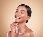 Face, eyes closed or makeup on happy woman in studio isolated on beige background for skincare. Facial smile, natural beauty or funny Indian girl laughing with glow or luxury self care cosmetics
