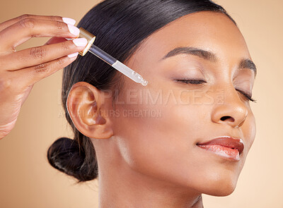 Buy stock photo Woman, dropper and retinol on face for skincare beauty or cosmetics against studio background. Calm beautiful female model applying oil drop to skin for hydration, moisturizer or facial treatment