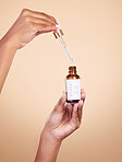 Hands, serum and pipette with bottle product in studio isolated on brown background. Skincare, dermatology and woman model with cruelty free hyaluronic acid, vegan retinol or essential oil cosmetics.