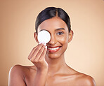 Portrait, skincare and cotton swab with a model woman in studio on beige background to promote beauty. Face, eye and exfoliate with an attractive young female posing for cosmetics or luxury wellness