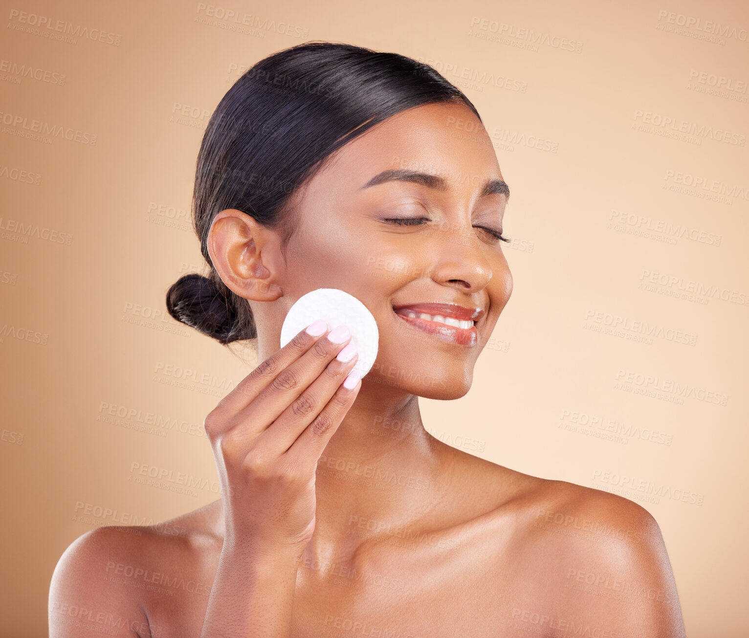 Buy stock photo Smile, makeup or happy woman with cotton pad in studio isolated on beige background for facial skincare. Glowing natural beauty or beautiful young Indian girl cleaning for self care or face wipes