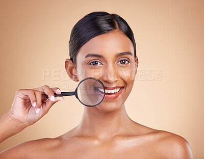 Buy stock photo Portrait, skincare and magnifying glass with a model woman in studio on a beige background searching for beauty. Face, investigation and smile with an attractive female looking for luxury cosmetics