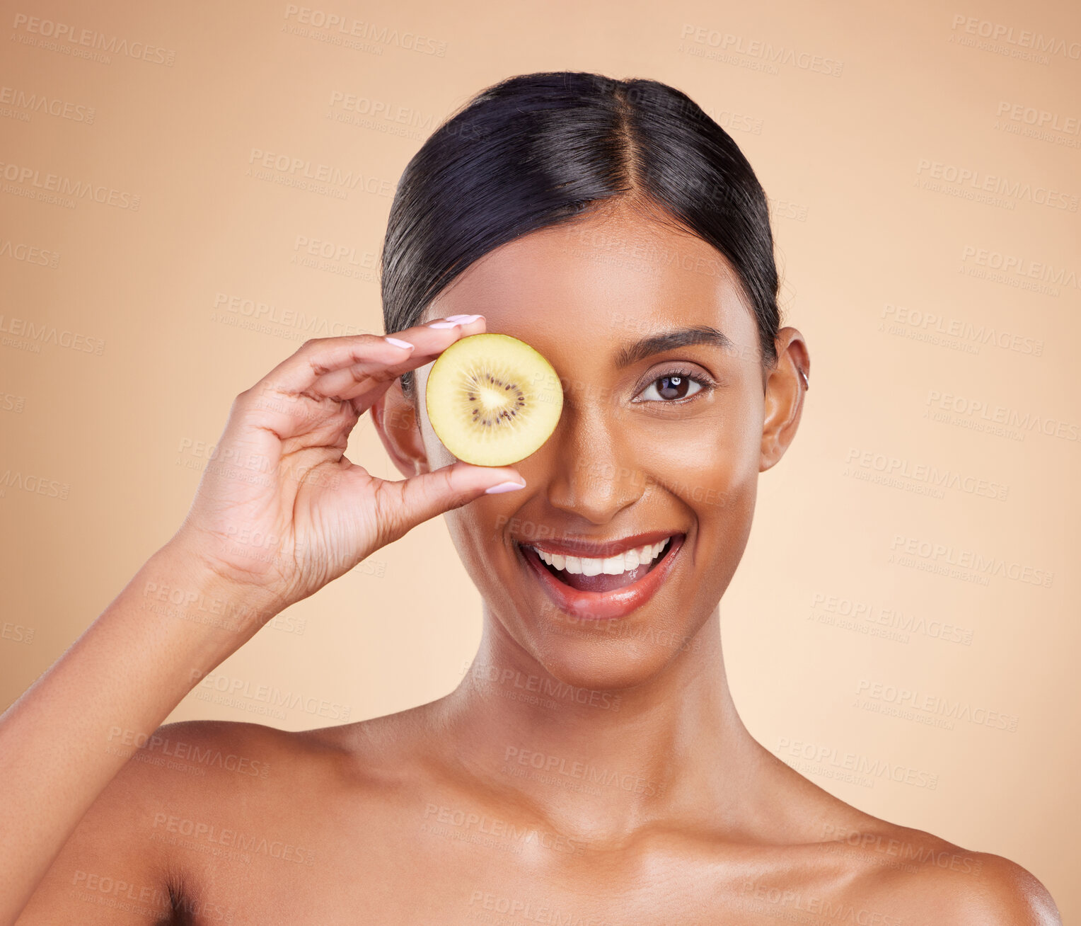 Buy stock photo Portrait, beauty and kiwi with a model woman in studio on a beige background to promote skincare. Face, eye and fruit with an attractive young female posing for organic, natural or luxury cosmetics