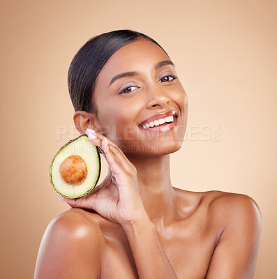 Buy stock photo Portrait, skincare and avocado with a model woman in studio on a beige background for beauty. Face, fruit and antioxidants with an attractive young female posing for organic or natural cosmetics