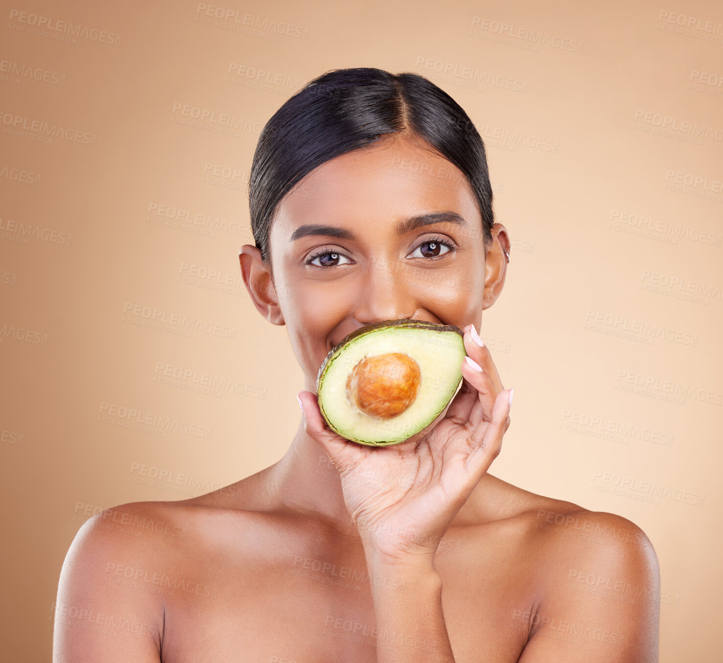 Buy stock photo Portrait, skin or avocado with a model woman in studio on a beige background to promote beauty. Face, eyes and fruit with an attractive young female posing for organic, natural or luxury antioxidants