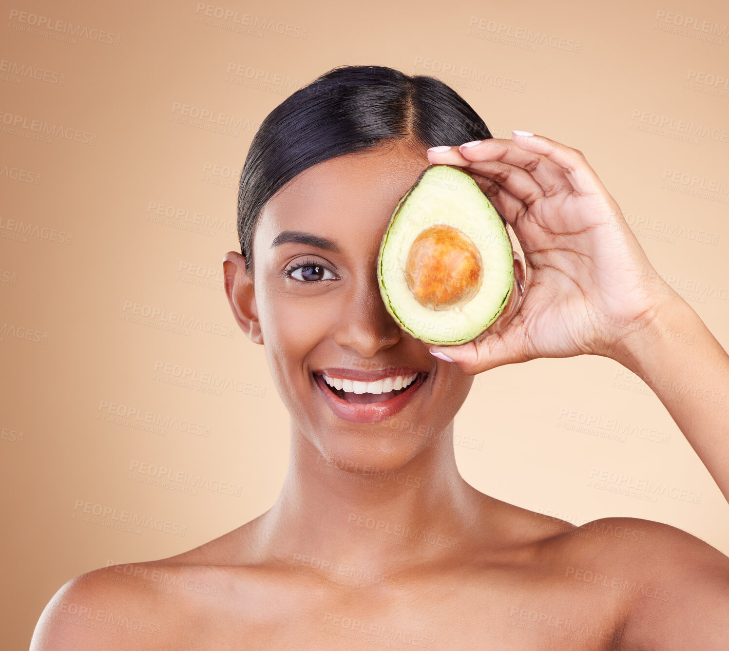 Buy stock photo Portrait, beauty and avocado with a model woman in studio on a beige background to promote skincare. Face, eye and fruit with an attractive young female posing for organic or natural antioxidants