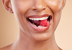 Woman, mouth and raspberry for skincare nutrition, dermatology or diet health plan against a studio background. Female lips with fruit for natural organic food, self care or eat for healthy wellness