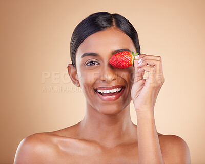 Buy stock photo Portrait, beauty and strawberry with a model woman in studio on a beige background to promote skincare. Face, eye and fruit with an attractive young female posing for organic or natural cosmetics