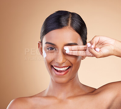 Buy stock photo Beauty, face cream and portrait of a woman in studio for skincare, dermatology and cosmetics. Happy Indian female model with smile and lotion on hand for self care moisture facial on brown background