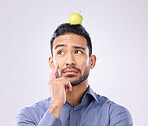 Apple, head balance and man thinking of fruit product choice for weight loss diet, healthcare food or detox. Nutritionist face, studio person and contemplating male vegan isolated on gray background