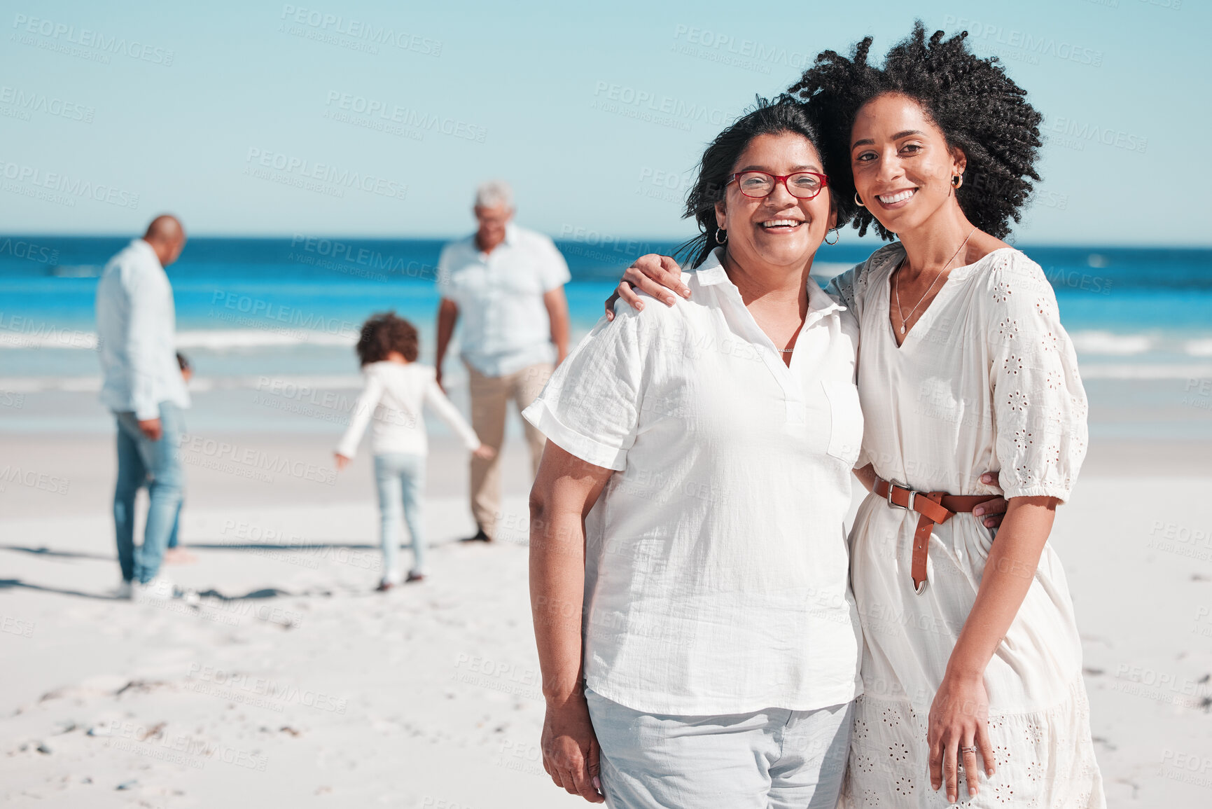 Buy stock photo Portrait, summer with a mother and daughter on the beach during summer while their family play in the background. Love, smile or nature with a senior woman and adult child bonding outdoor together