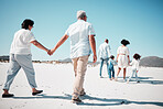 Elderly couple, holding hands and family at beach with back for walk, freedom and vacation together with love. Old man, woman and grandchildren by ocean for walking, wellness and journey in sunshine