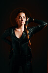 Woman, warrior and costume of vigilante in cosplay ready for battle, war or game against a dark studio background. Female in black leather uniform with sword and guns for halloween or hunger games