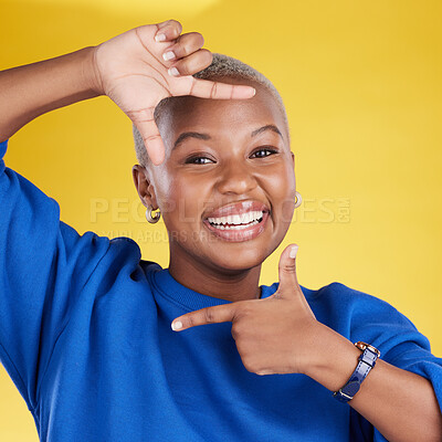 Buy stock photo Portrait, frame and hand gesture with a black woman in studio on a yellow background feeling happy. Hands, smile and focus with an attractive young female finger framing her face against a color wall