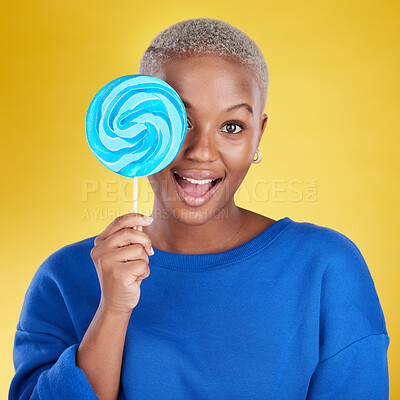 Buy stock photo Excited, portrait and black woman with a lollipop in studio for dessert, sweet treat or craving. Happy, surprise and face of African female model posing with blue candy isolated by yellow background.