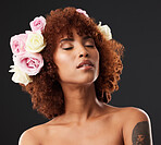 Artistic, creative and woman with flowers in hair isolated on a black background in a studio. Calm, peaceful and a beautiful girl with self love, floral look and creativity on a dark backdrop