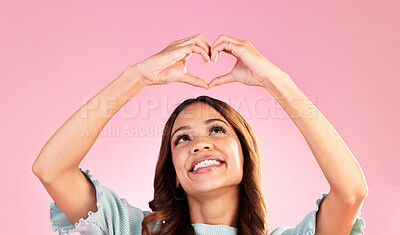 Buy stock photo Happy, heart hands and smile with woman in studio for romance, positive and kindness. Love, support and emoji with female and shape isolated on pink background for emotion, hope and gesture 