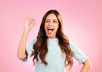 Buy stock photo Wink, studio and woman with a perfect hand gesture, excitement and positive face expression. Happy, smile and young female model from Colombia with a ok sign language isolated by a pink background.