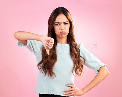 Buy stock photo Sad, thumb down and portrait of a woman in a studio with an upset, moody or disappointed face. Loser, unhappy and young female model posing with a angry hand gesture isolated by a pink background.